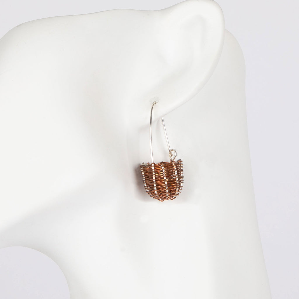 Copper and silver dilly bag earring on a white mannequin with a white background