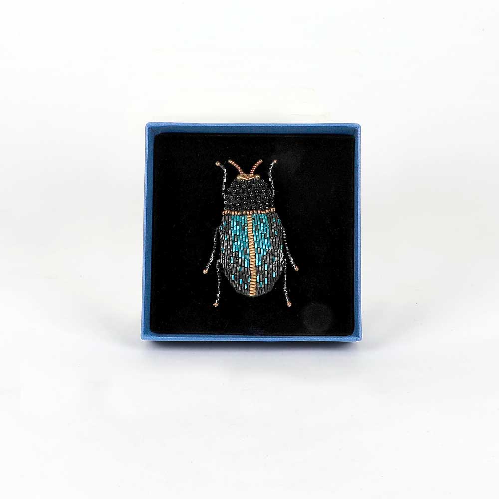 Trovelore Beaded nature brooch hand made in india on white background. Electric blue beetle