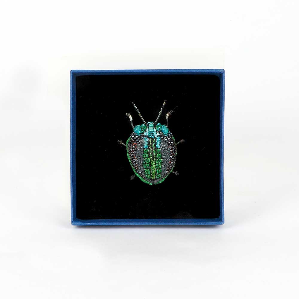 Trovelore Beaded nature brooch hand made in india on white background. Green leaf beetle