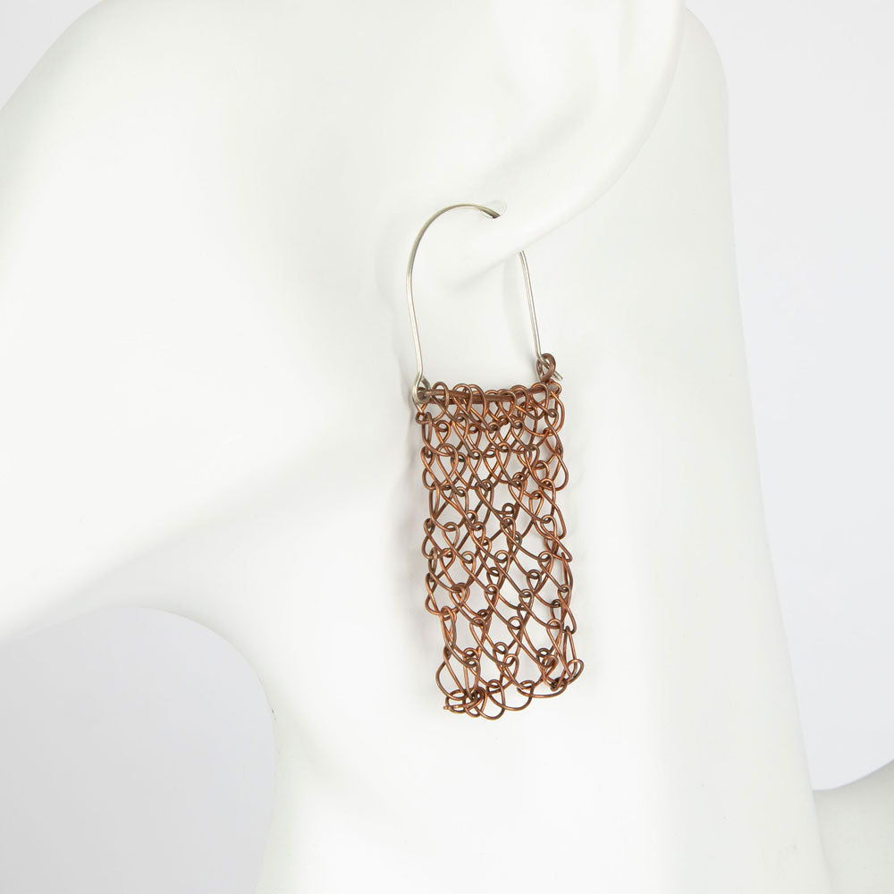 Copper and silver handwoven string bag earrings on a white mannequin background
