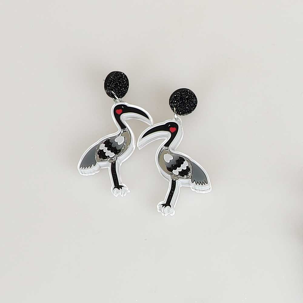 Ibis dented diva earrings. Acrylic ibis hangs from orange mirror disc ear stud. Photographed on white background for Australian Museum Shop online