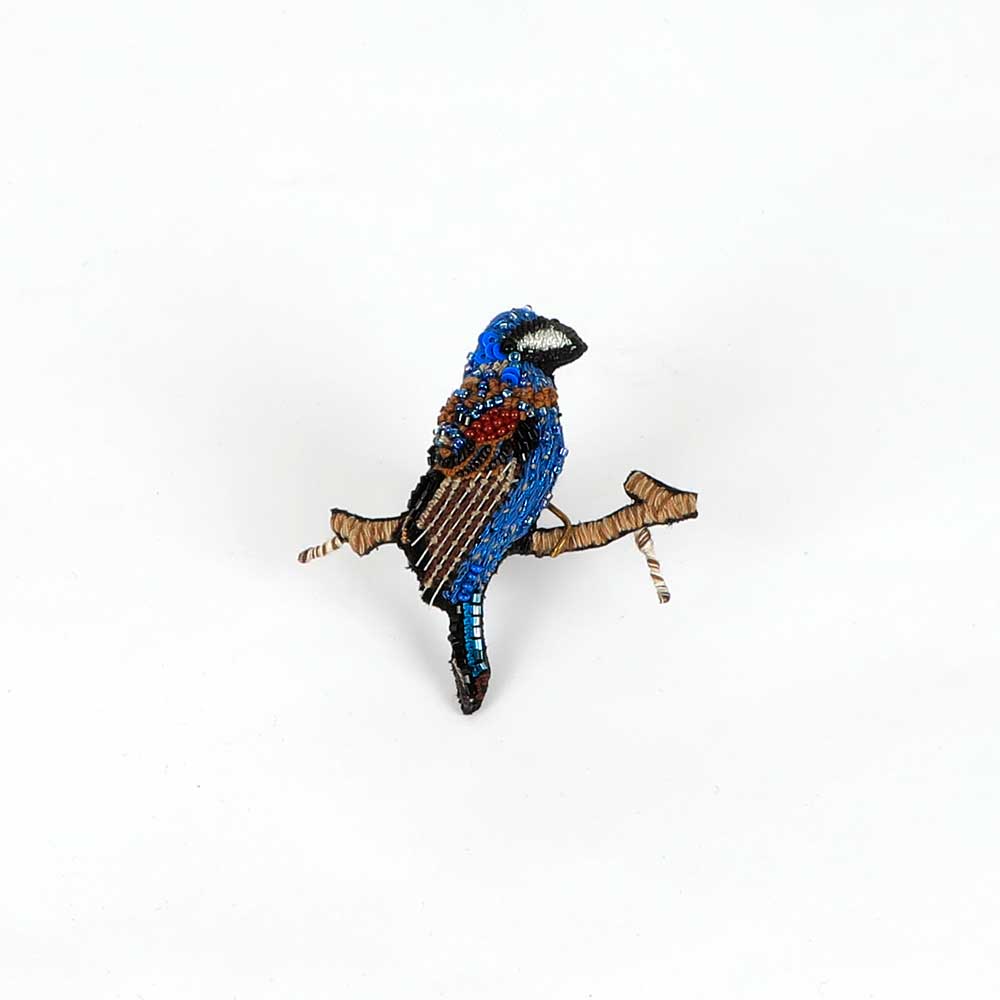 Beaded nature brooch hand made in india on white background. Indigo bunting bird brooch