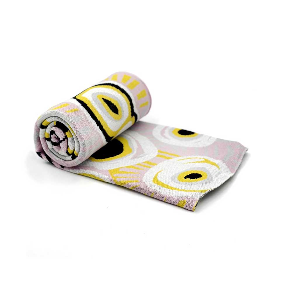 Rolled cotton throw with white, yellow, black, pink colouring and artwork by Murdie Nampijinpa Morris, on white background