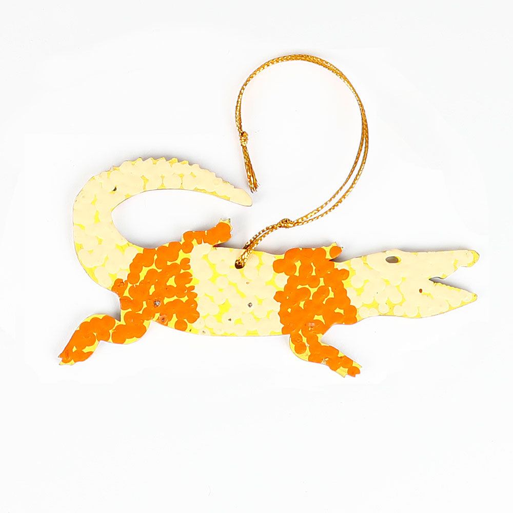 Decorative crocodile ornament from Warlukurlangu artists cooperative, with orange and yellow pattern on a white background