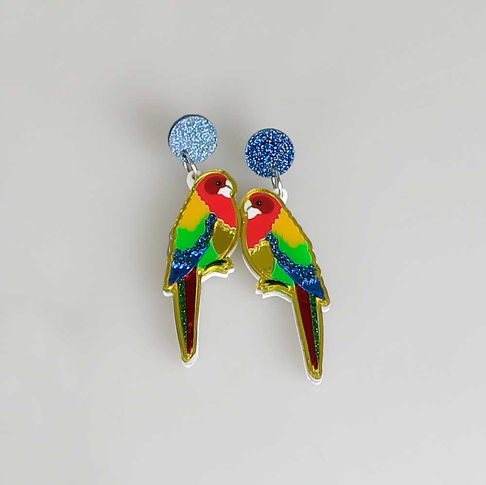 Rosella dented diva earrings. Acrylic rosella hangs from blue sparkle disc ear stud. Photographed on white background for Australian Museum Shop online