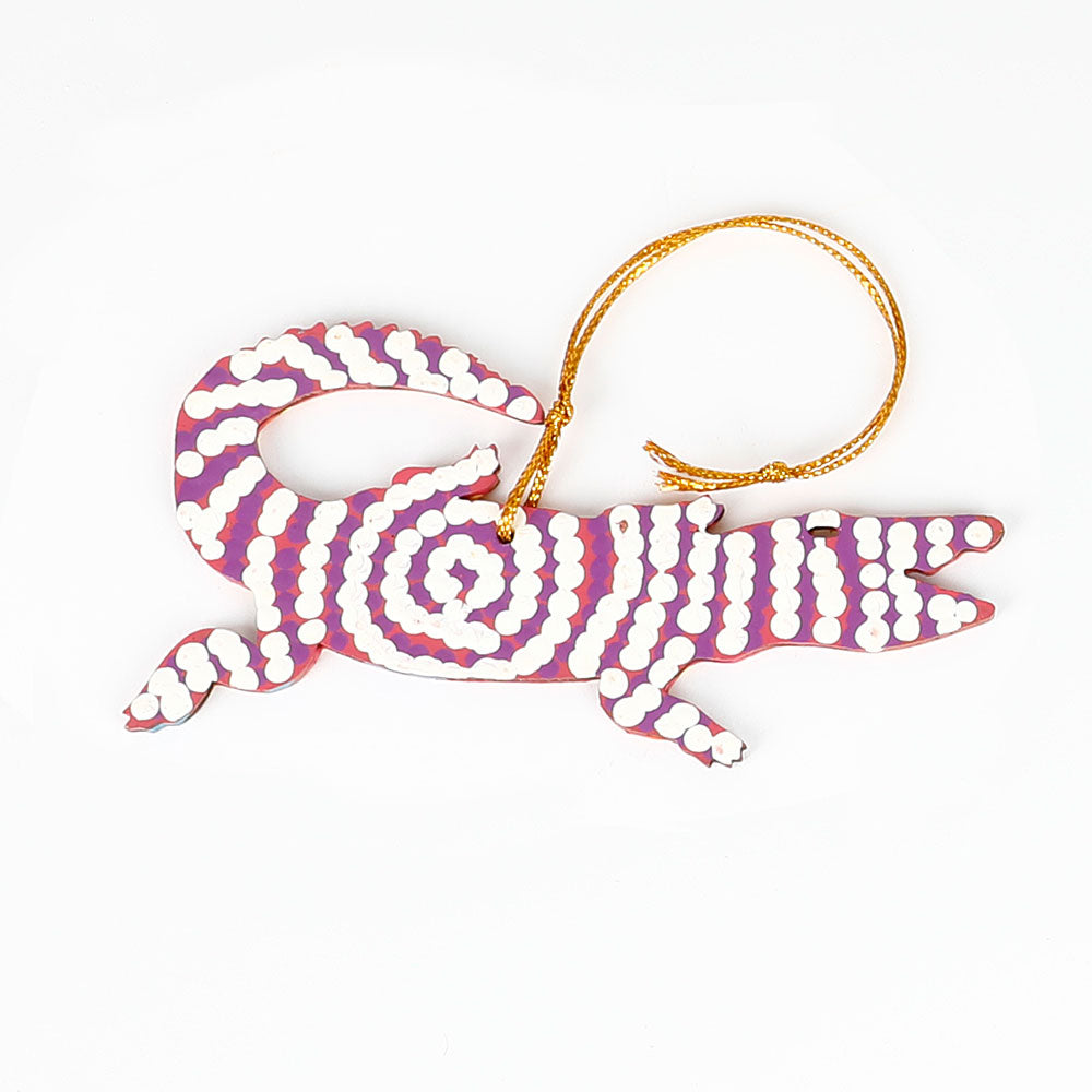 Decorative crocodile ornament from Warlukurlangu artists cooperative, with purple white pattern on a white background