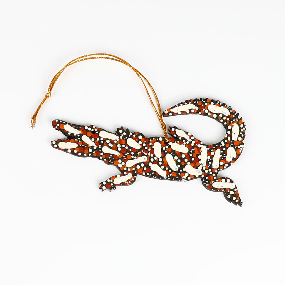 Decorative crocodile ornament from Warlukurlangu artists cooperative, with white tracks pattern on a white background